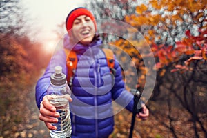 The girl is holding out a bottle of water.