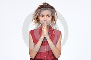 Girl holding palms pressed together in front of her, asking for forgiveness