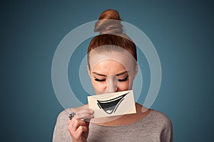 Girl holding paper with funny smiley drawing on gradient background