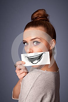 Girl holding paper with funny smiley drawing on gradient background
