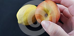 Girl holding a peach in fingers over yellow fresh lemon