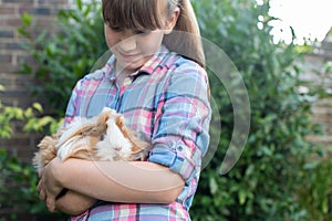 Girl Holding Pet Guinea Pig Outdoors In Garden