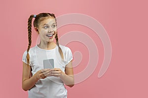 Girl holding phone, excited by content on pink