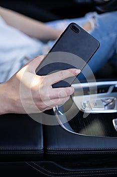 Girl holding phone in hands while sitting in the car.