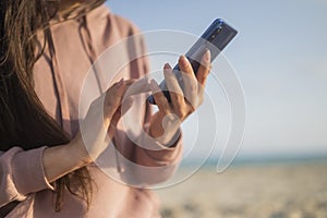 Girl holding phone smartphone in hands on the seashore