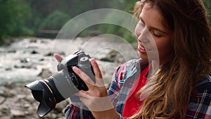 Girl holding photo camera in hands. Photographer looking pictures on camera