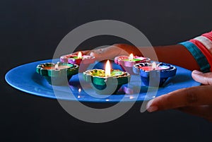 A girl holding a plate of diyas to clebrate diwali