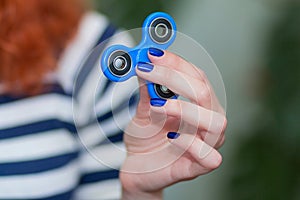 A girl is holding a popular toy fidget spinner in her hands. Stress relief. Anti stress and relaxation fidgets spinner.