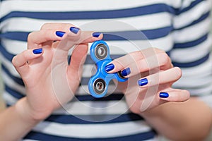 A girl is holding a popular toy fidget spinner in her hands. Stress relief. Anti stress and relaxation fidgets, spinner for tired.