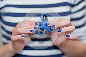 A girl is holding a popular toy fidget spinner in her hands. Stress relief. Anti stress and relaxation fidgets, spinner for tired