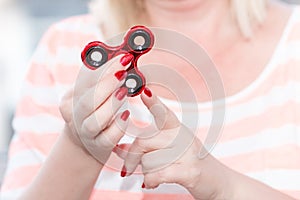 A girl is holding a popular toy metallic red fidget spinner.