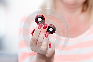 A girl is holding a popular toy metallic red fidget spinner.