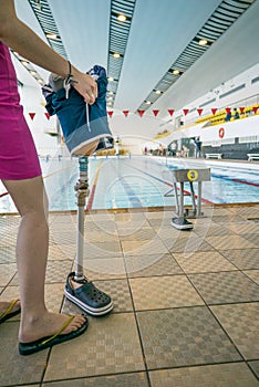 Girl holding prosthetic leg in paralympic sports pool