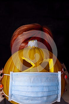 Girl holding pumpkin with facial mask