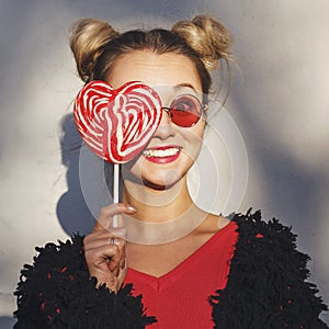 Girl holding a red lollipop in shape of heart