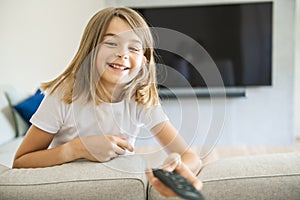 A girl holding remote control and watching TV show