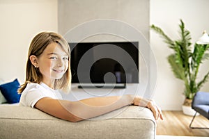 A girl holding remote control and watching TV show