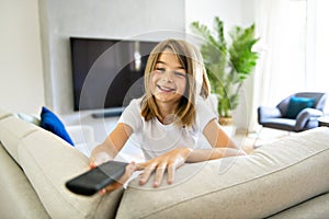 A girl holding remote control and watching TV show