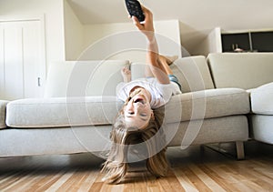 A girl holding remote control and watching TV show