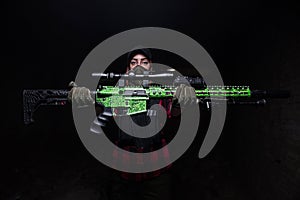 Girl holding rifle on dark background