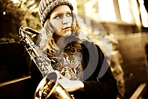 Girl holding saxophone, looking far away