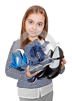 The girl is holding several pairs of shoes.