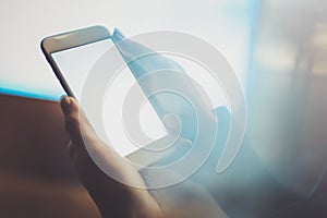 Girl holding smartphone with white empty screen in night atmospheric city.Closeup on blurred background.