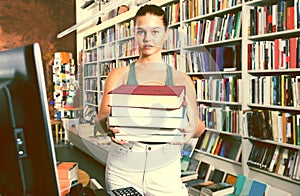 Girl holding a stack of books in a bookstore