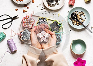 Girl holding a star shaped homemade little birdseed cake made from peanut nuts and coconut fat.