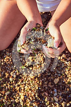 A girl is holding stones in hands in a shape of a heart