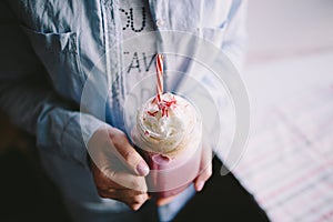 Girl is holding stylized mason jar cup of pink coffee with cream, marshmallow and decoration. Milk shake, cocktail. Unicorn coffee