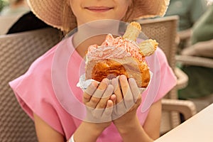 Girl holding sweet sandwich, called brioche con gelato, a brioche bun stuffed with a fat smear of strawberry ice cream.