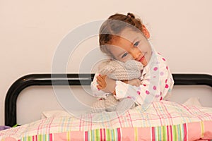 Girl holding teddy in bed