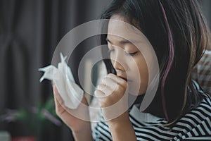 A girl is holding a tissue and coughing