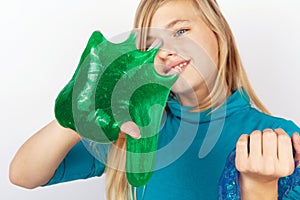 Girl holding a transparent blue glitter and a green slime on her hands