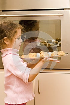 Girl holding tray of cookies to bake
