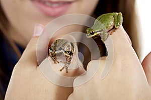 Girl holding two Oregon tree frogs up close