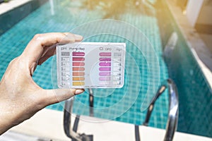 Girl holding water testing test kit over blurred swimming pool background