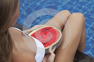 Girl holding watermelon near pool