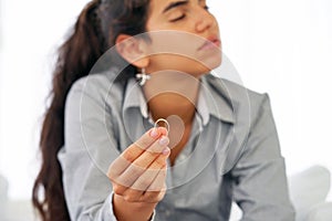 A girl holding a wedding ring doubtfully. Focus on the ring