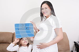 Girl holding a 30 weeks sign to her expectant mother