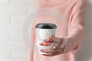 Girl holding white paper cup of takeaway coffee in the hand. Place for your text or log. Winter and Christmas time concept