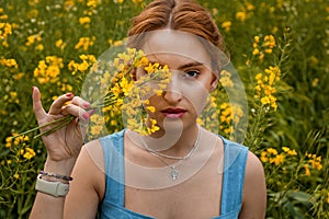 Girl holding a yellow rapeseed flower in the field