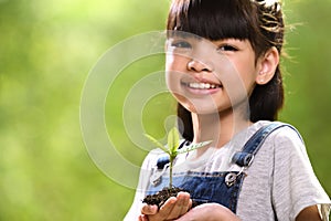 A girl holding a young plant in her hands with a hope of good environment, selective focus on plant