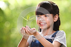 A girl holding a young plant in her hands with a hope of good environment, selective focus on plant