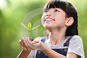 A girl holding a young plant in her hands with a hope of good environment, selective focus on plant