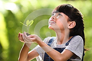 A girl holding a young plant in her hands with a hope of good environment, selective focus on plant