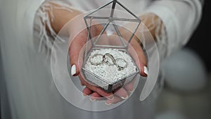 The girl holds a beautiful glass box in her hands with wedding rings. Wedding rings in a beautiful box.