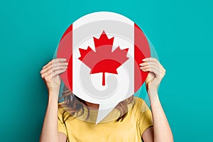 girl holds blank white speech bubble with canadian flag isolated on blue background