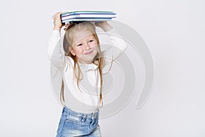 A girl holds books on her head. Isolated over white background